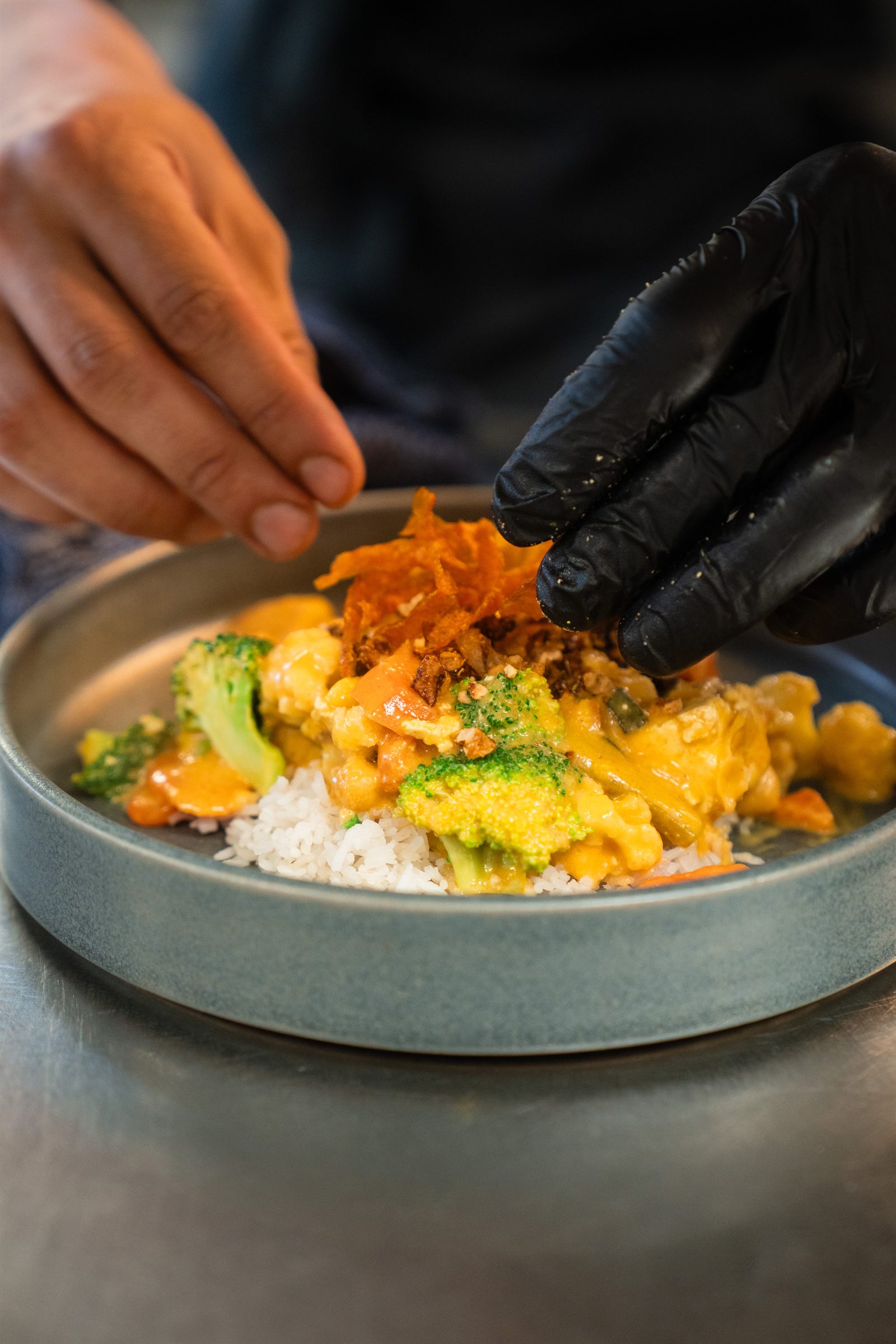 A cook finishing a curry in the kitchen