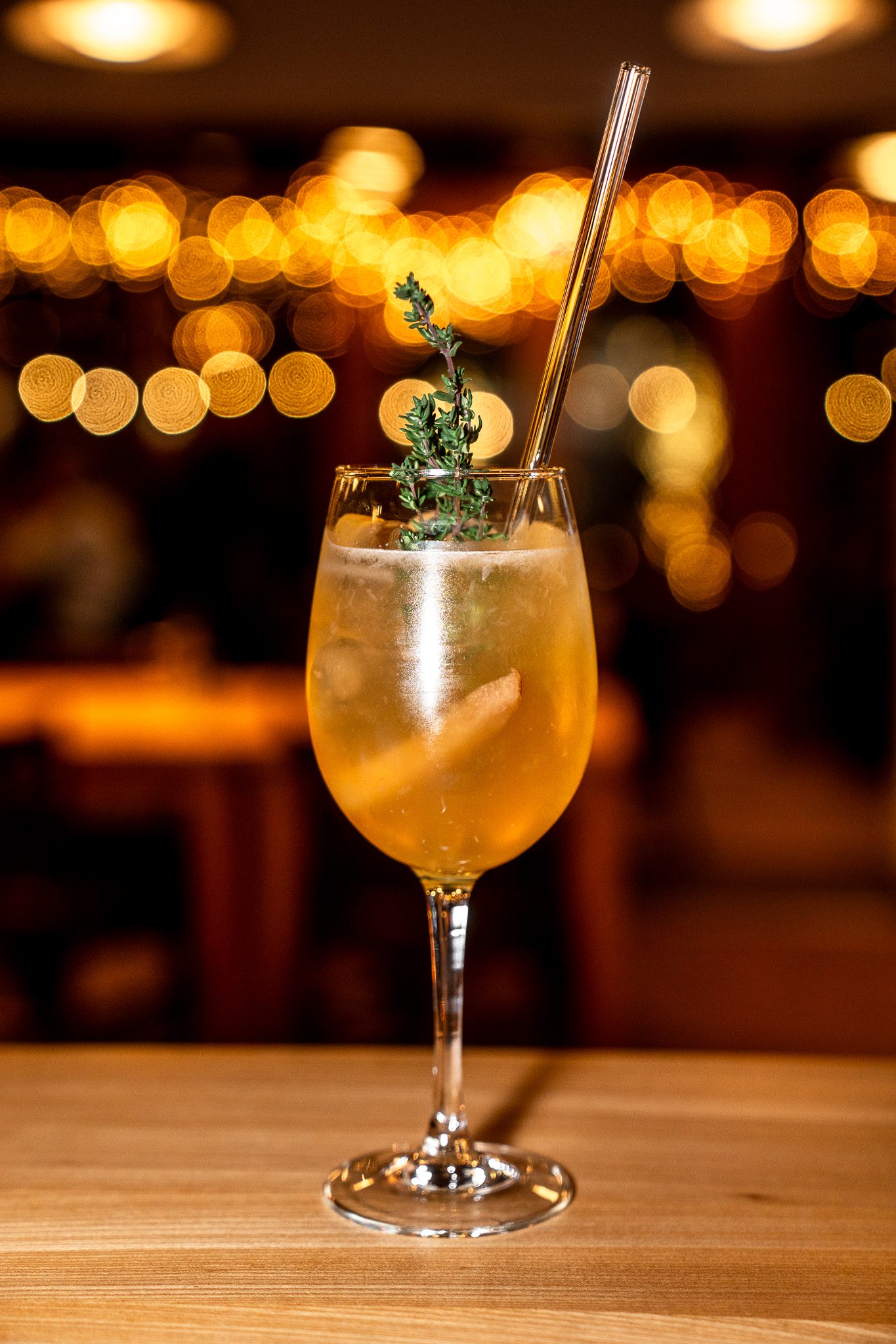 A house spritz with thyme and citrus against warm bokeh lights